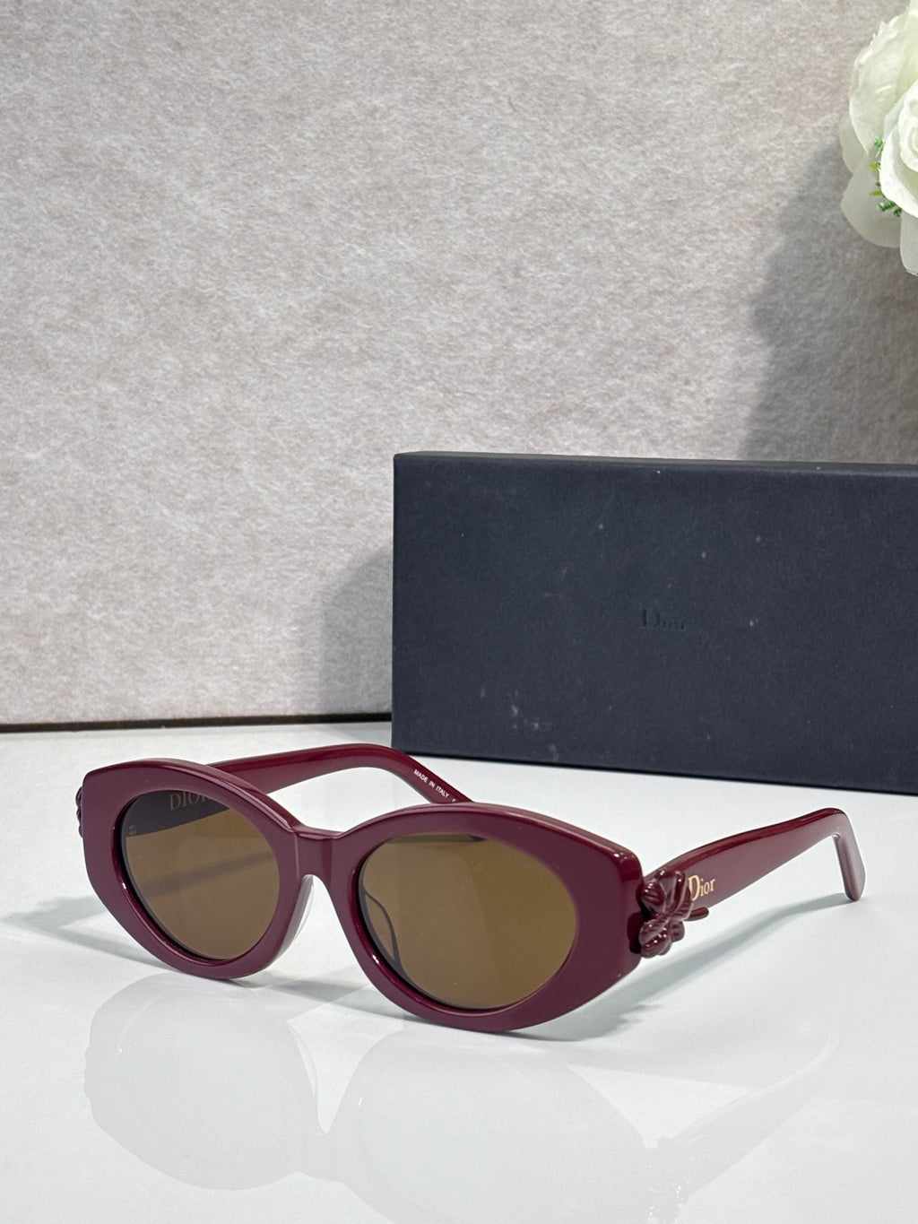 Burgundy round sunglasses with floral temple accents and brown-tinted lenses