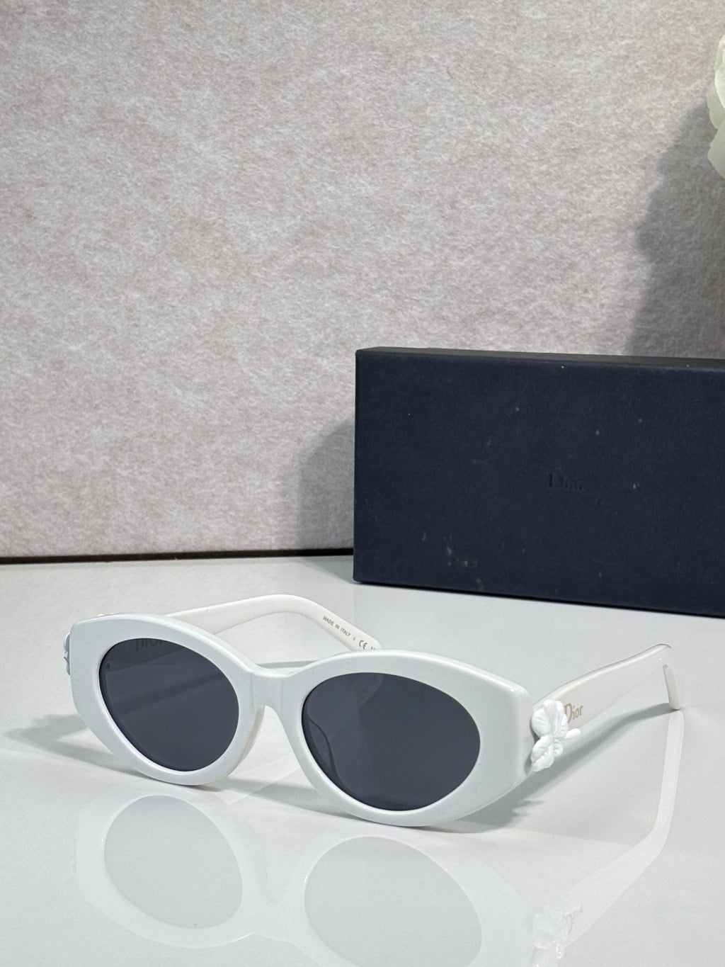 White round sunglasses with dark-tinted lenses and white floral temple accents