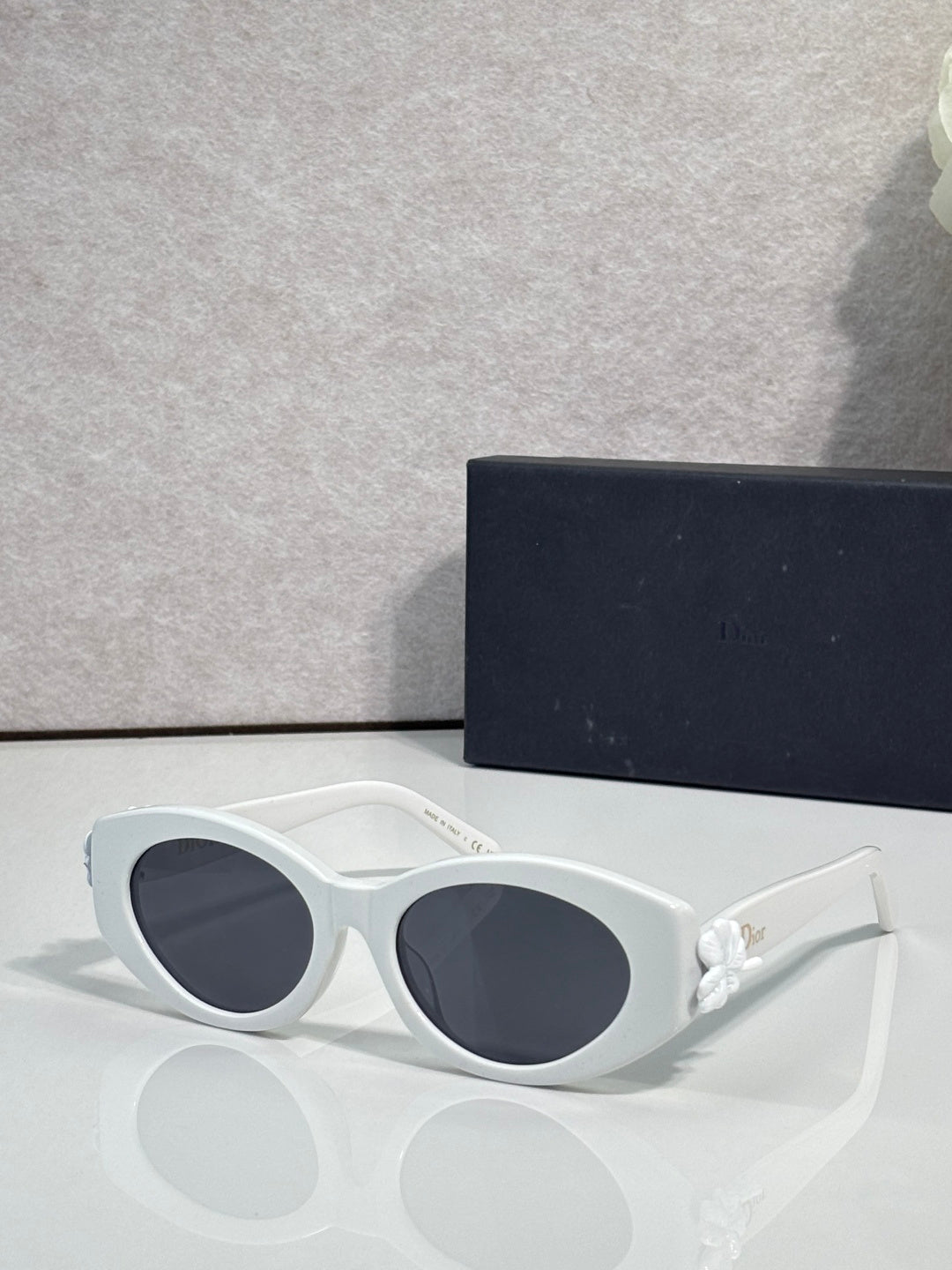 White round sunglasses with dark-tinted lenses and white floral temple accents
