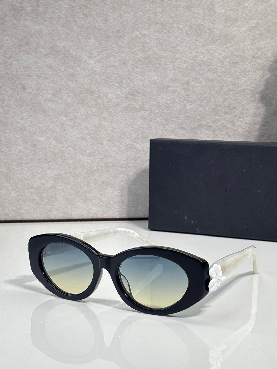 White round sunglasses with blue-tinted lenses and floral temple accents