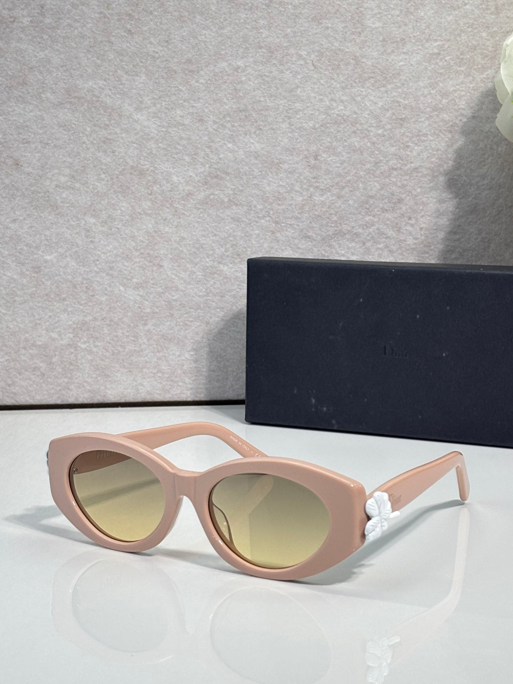 Blush pink round sunglasses with green-tinted lenses and floral temple accents