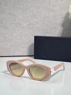 Blush pink round sunglasses with green-tinted lenses and floral temple accents