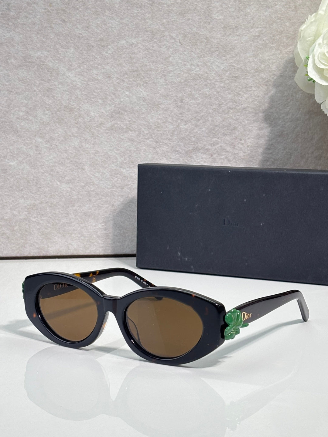 Black round sunglasses with green floral temple accents and dark-tinted lenses