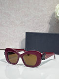 Maroon Dior glasses with rounded square lenses and gold floral charm on the temple.