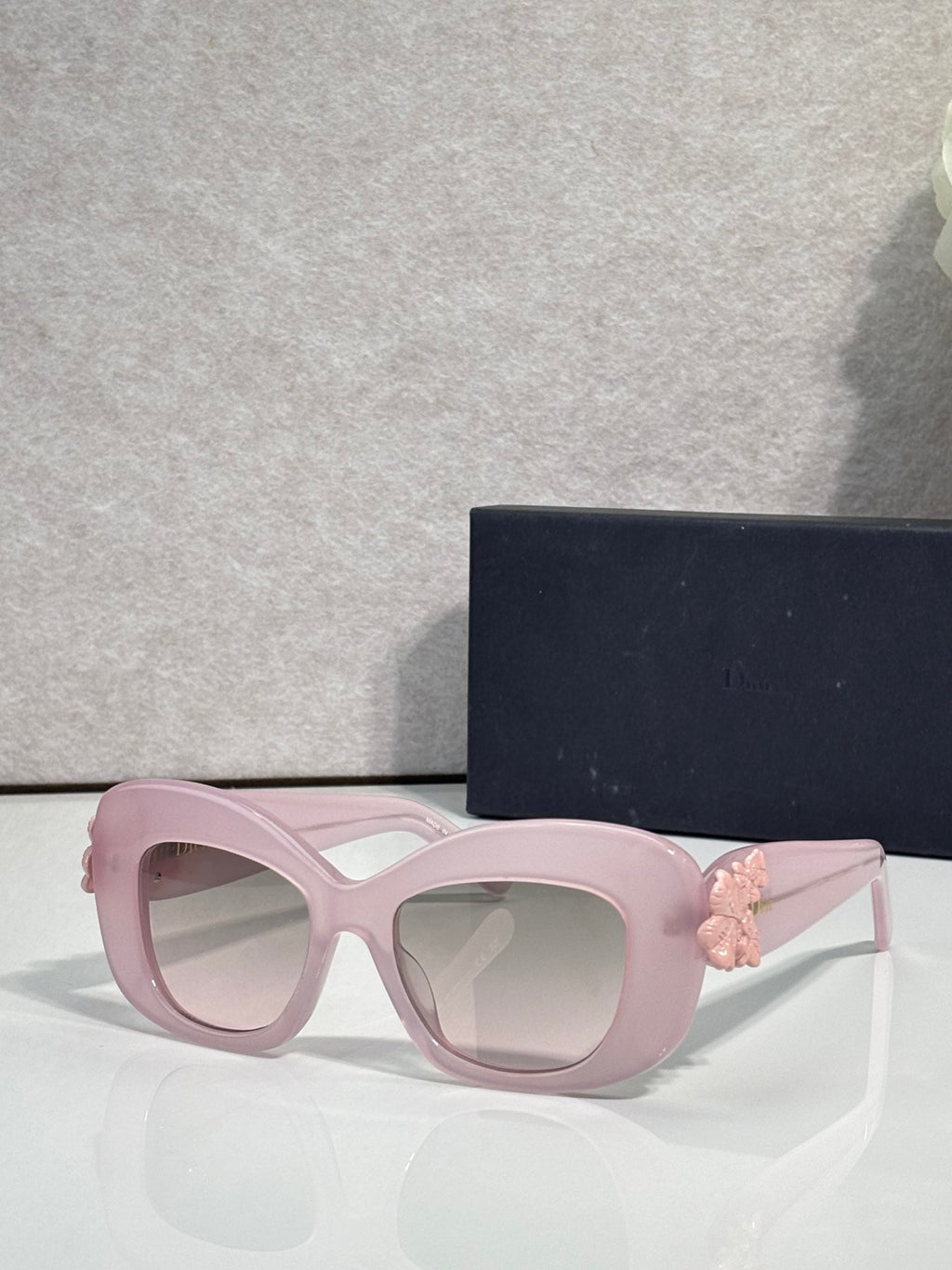 Light pink Dior glasses with rounded square lenses and pink floral charm on the temple.