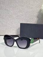 Black Dior glasses with rounded square lenses and multicolor floral charm on the temple.