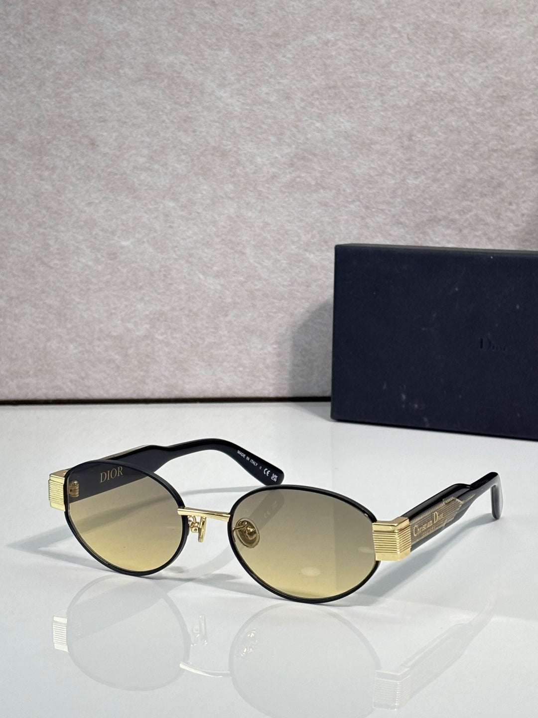 Gold cat-eye sunglasses with amber-tinted lenses and black temple Dior branding