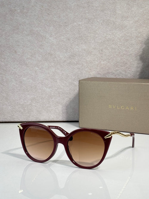 Sunglasses, burgundy rounded frames with gold-tone temple tips and tinted lenses
