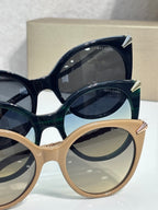 Stacked sunglasses with dark blue, deep green, and beige rounded frames