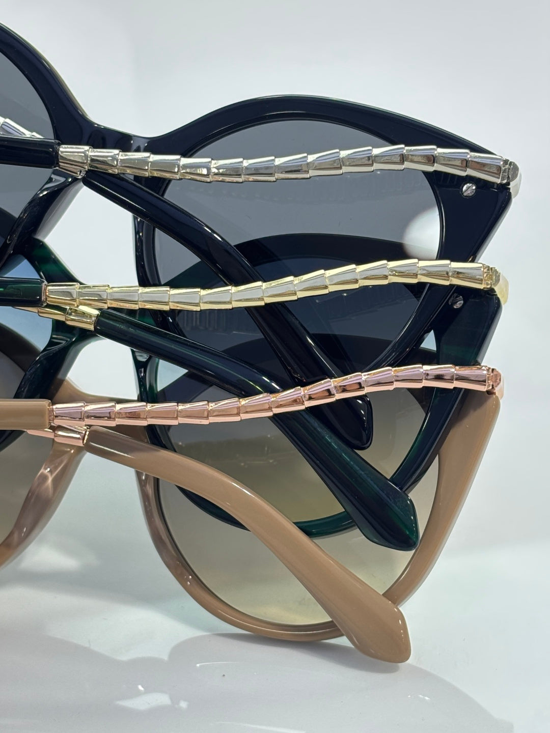 Sunglasses temples in navy, green, and rose tones with gold-tone hinge accents