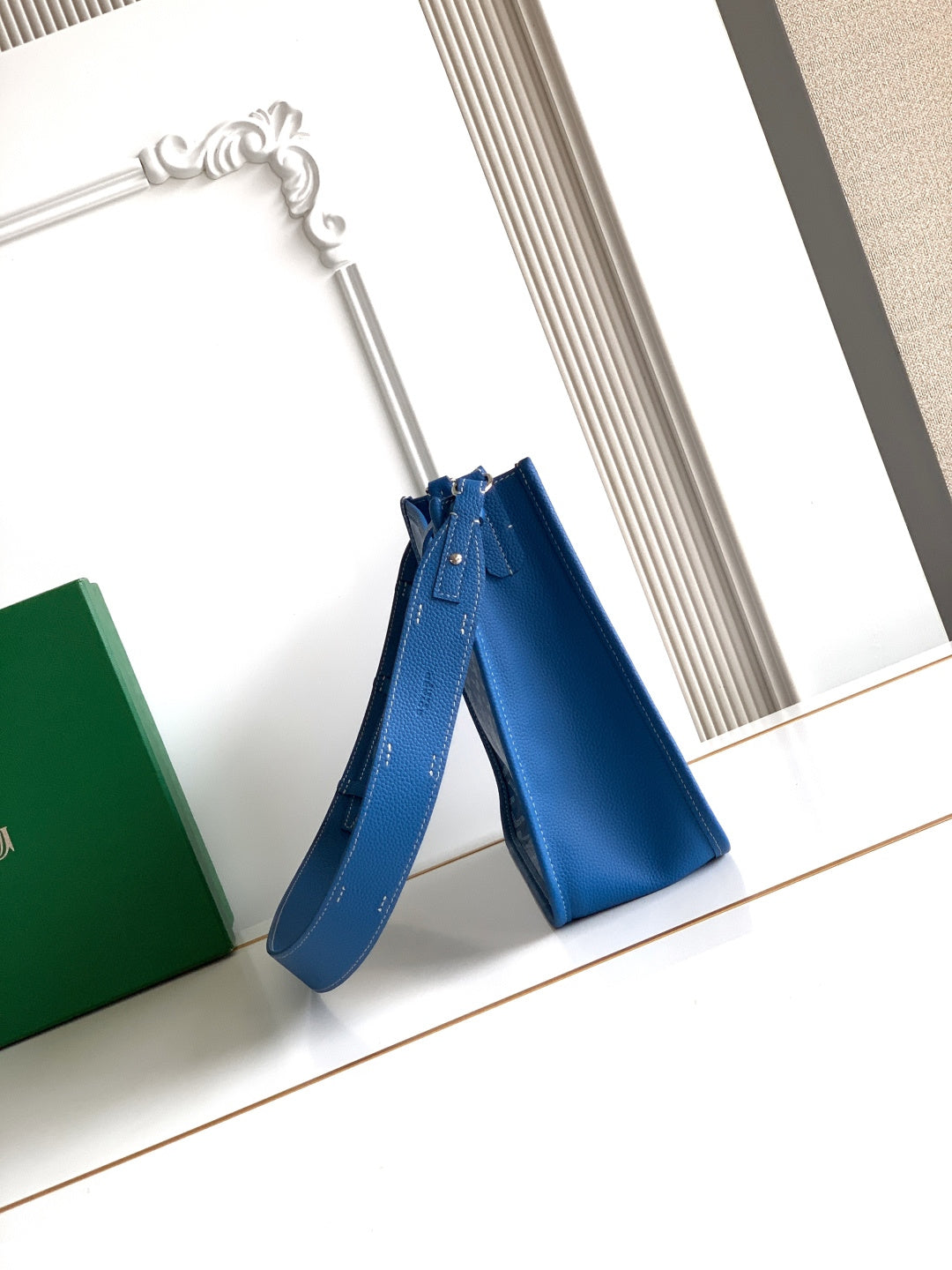 Goyard blue crossbody bag with patterned body, adjustable shoulder strap, and top handle