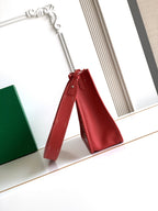 Red handbag with fold-over strap detail and long shoulder strap