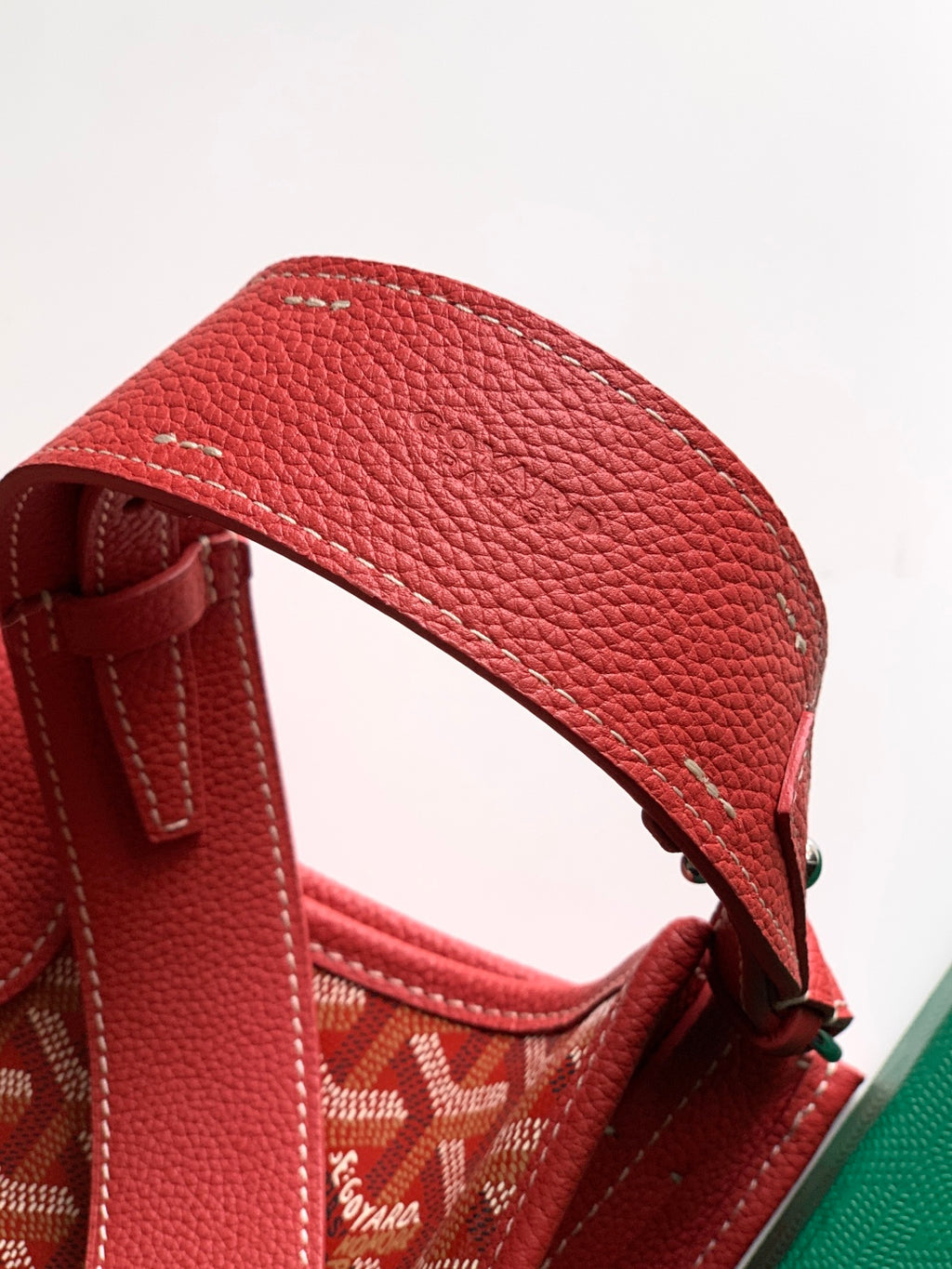 Red leather shoulder strap with adjustable buckle on textured handbag