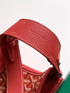 Red leather shoulder strap with adjustable buckle on textured handbag