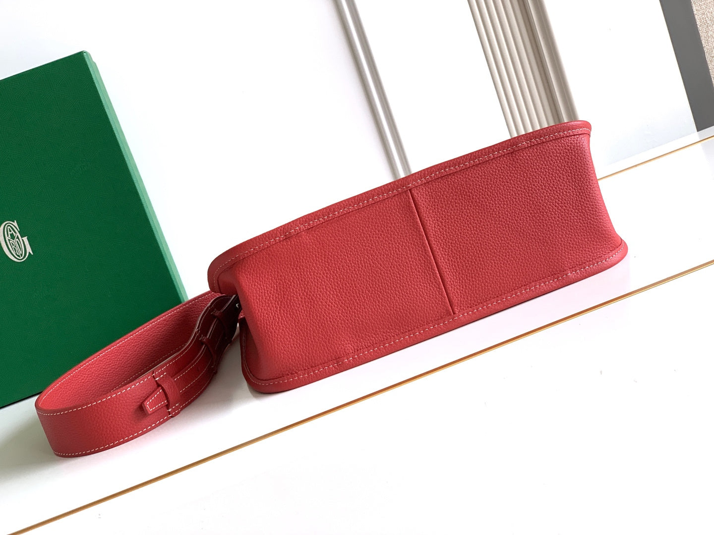 Red leather handbag with top tab closure and attached crossbody strap