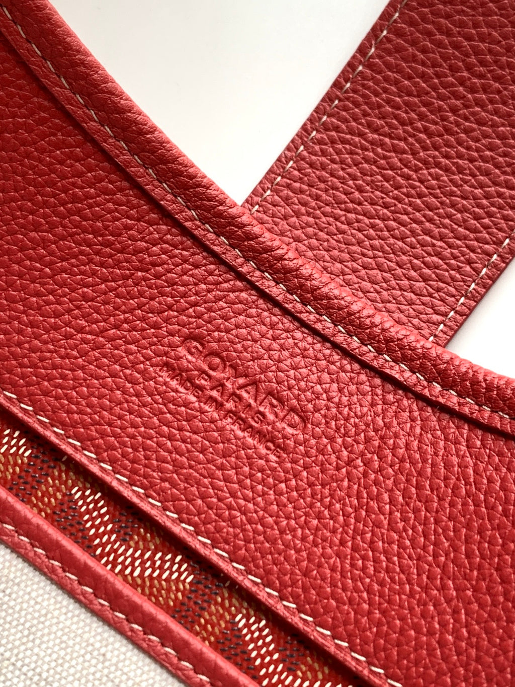 Red textured leather handbag with stitched edge and embossed pattern detail