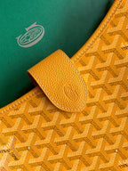 Close-up of mustard leather tab and embossed monogram fabric on the bag