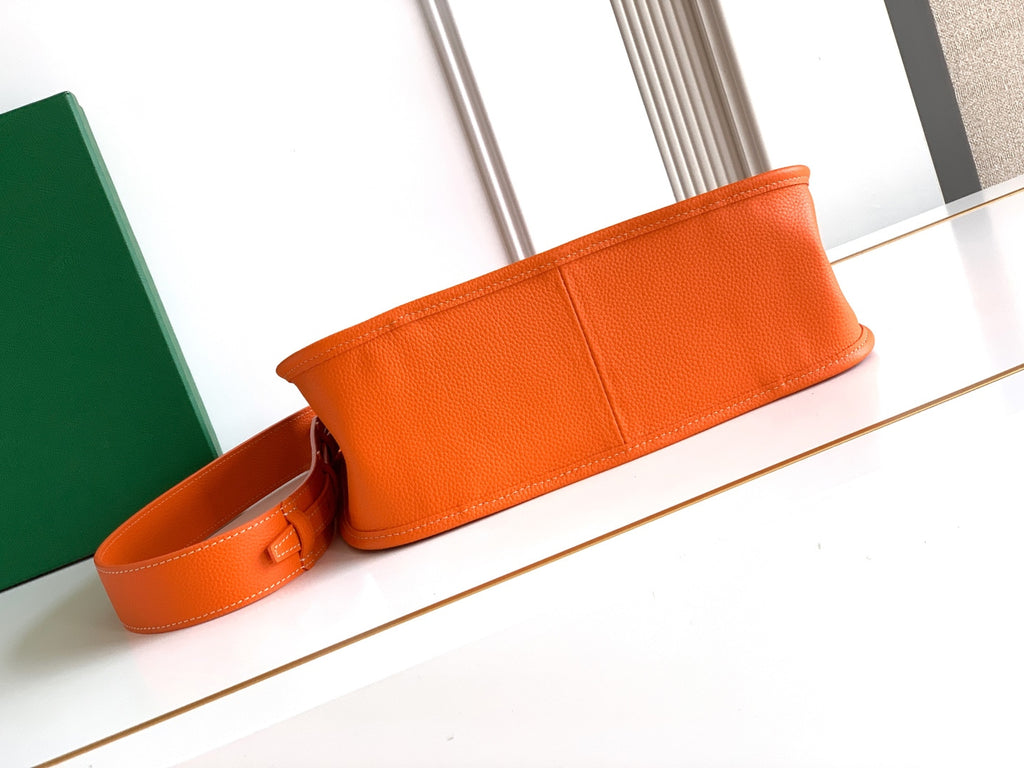 Orange leather strap bag with wide front panel and stitched trim