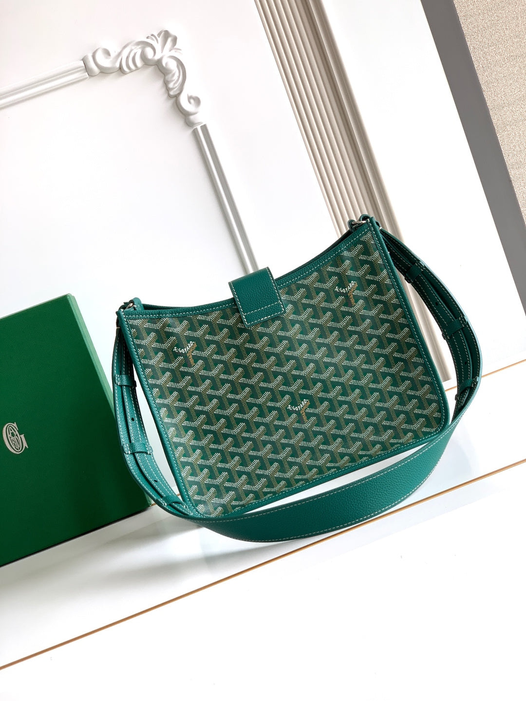 Teal patterned canvas Goyard bag with leather wrist strap and front flap