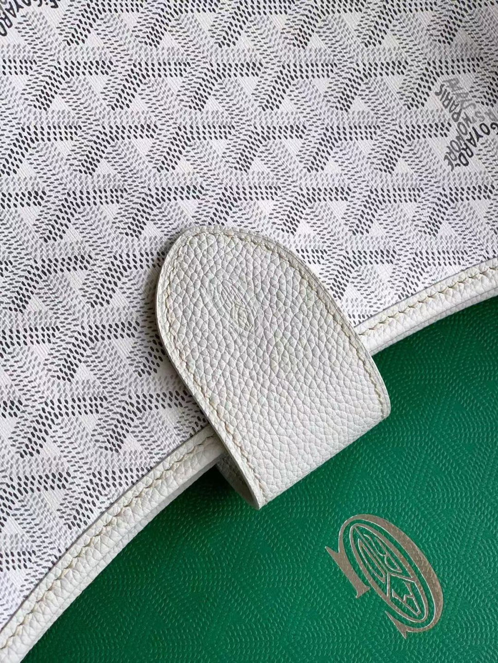 White Goyard tote bag corner with snap tab and embossed texture close-up