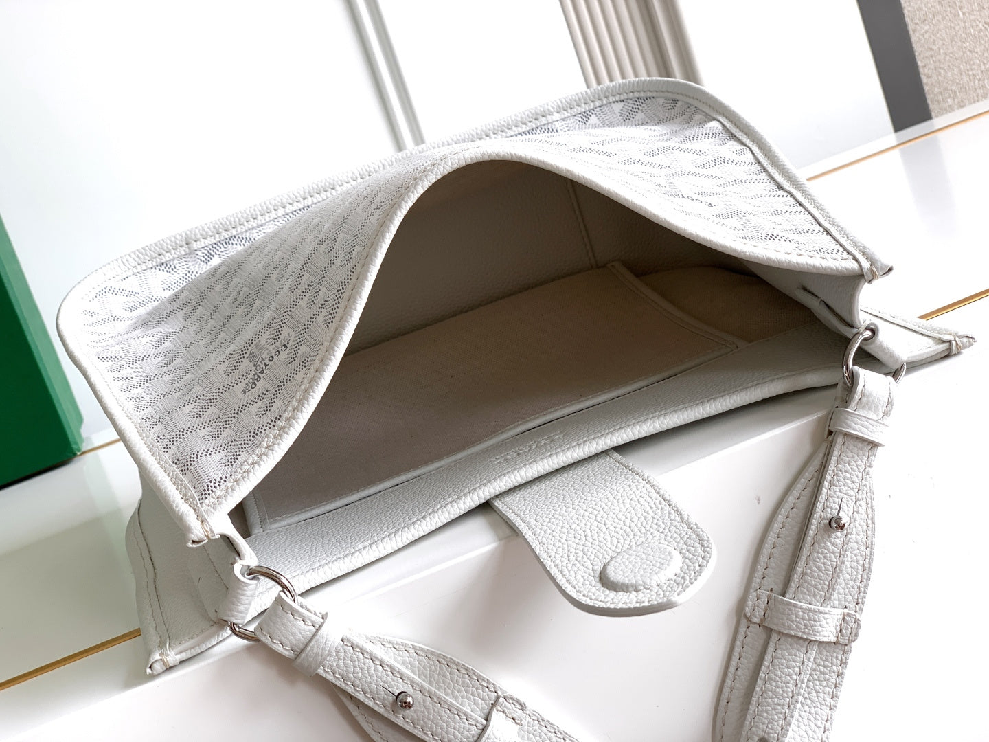 Open top of a white Goyard tote bag showing interior and side pocket