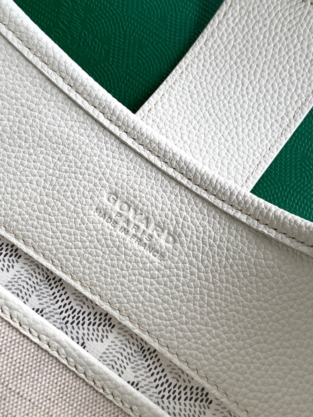 White Goyard tote bag close-up of embossed logo and stitched seam on strap