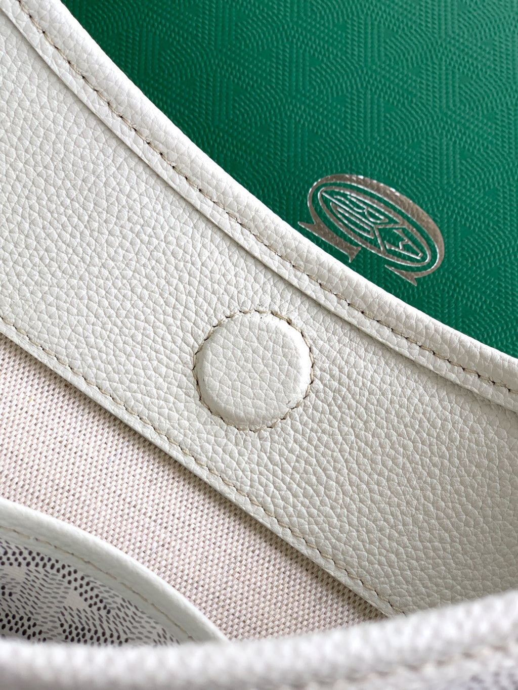 White Goyard tote bag clasp and green logo medallion on front strap