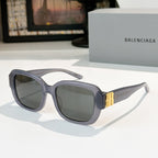 Sunglasses, light gray-blue square frames with tinted lenses and gold bar accents.