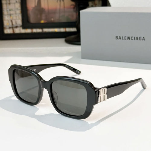 Sunglasses, black square frames with dark lenses and gold bar accents.