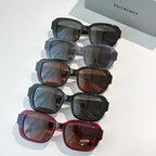 Stacked square sunglasses in dark, gray, brown, and burgundy with gold accents.