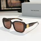 Sunglasses, dark tortoiseshell square frames with gold bar accents.