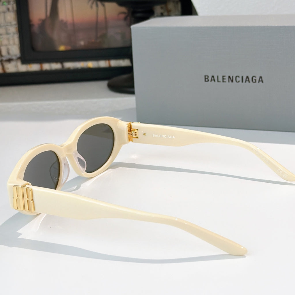 Cream cat-eye sunglasses with dark lenses and gold hinge detail