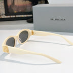Cream cat-eye sunglasses with dark lenses and gold hinge detail
