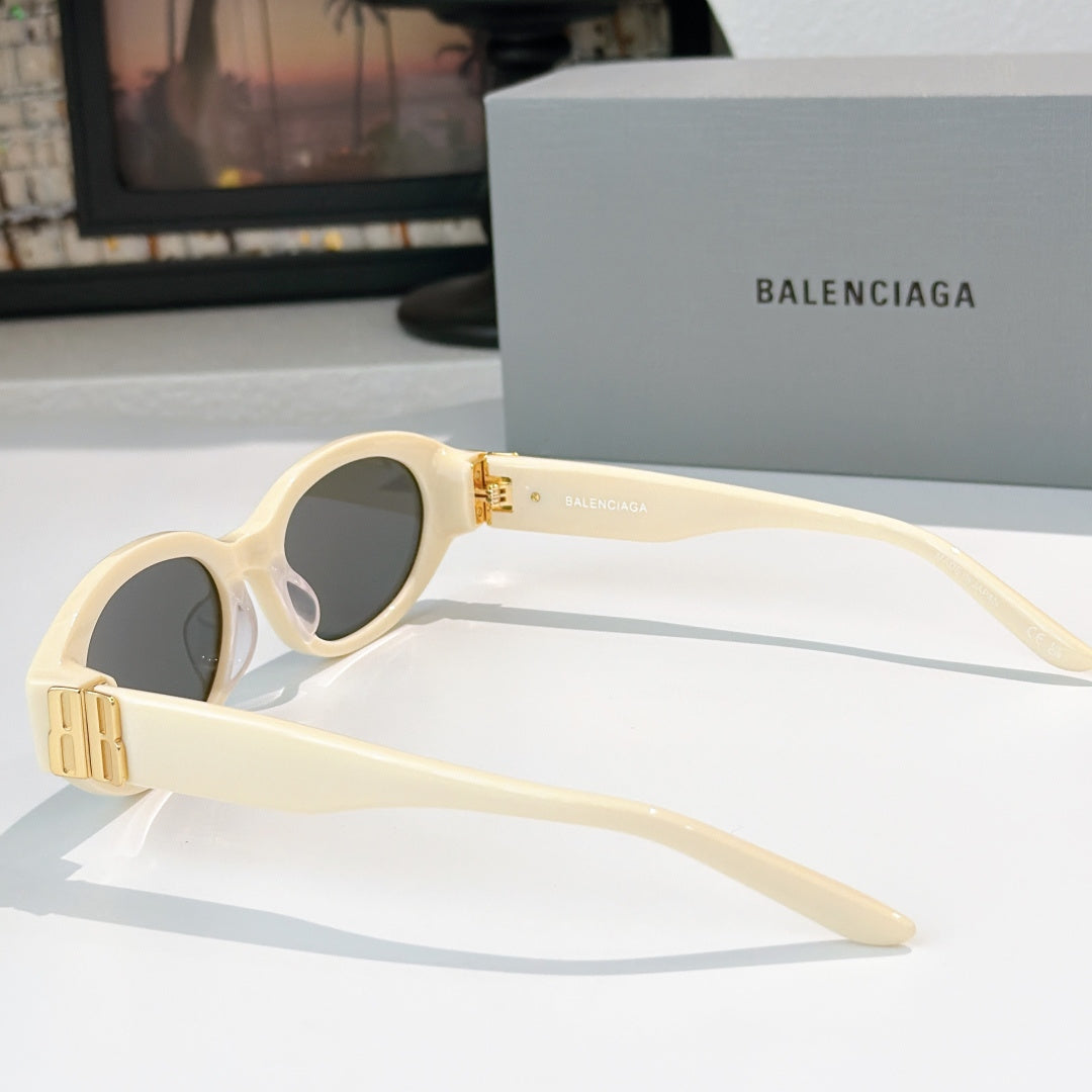 Cream cat-eye sunglasses with dark lenses and gold hinge detail