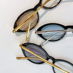 Set of metal-and-tortoise sunglasses with gold arms and tinted lenses, oval frames.