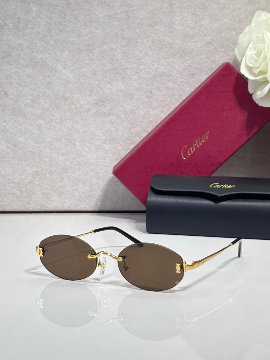 Round sunglasses with gold frame, dark temples, and brown tinted lenses
