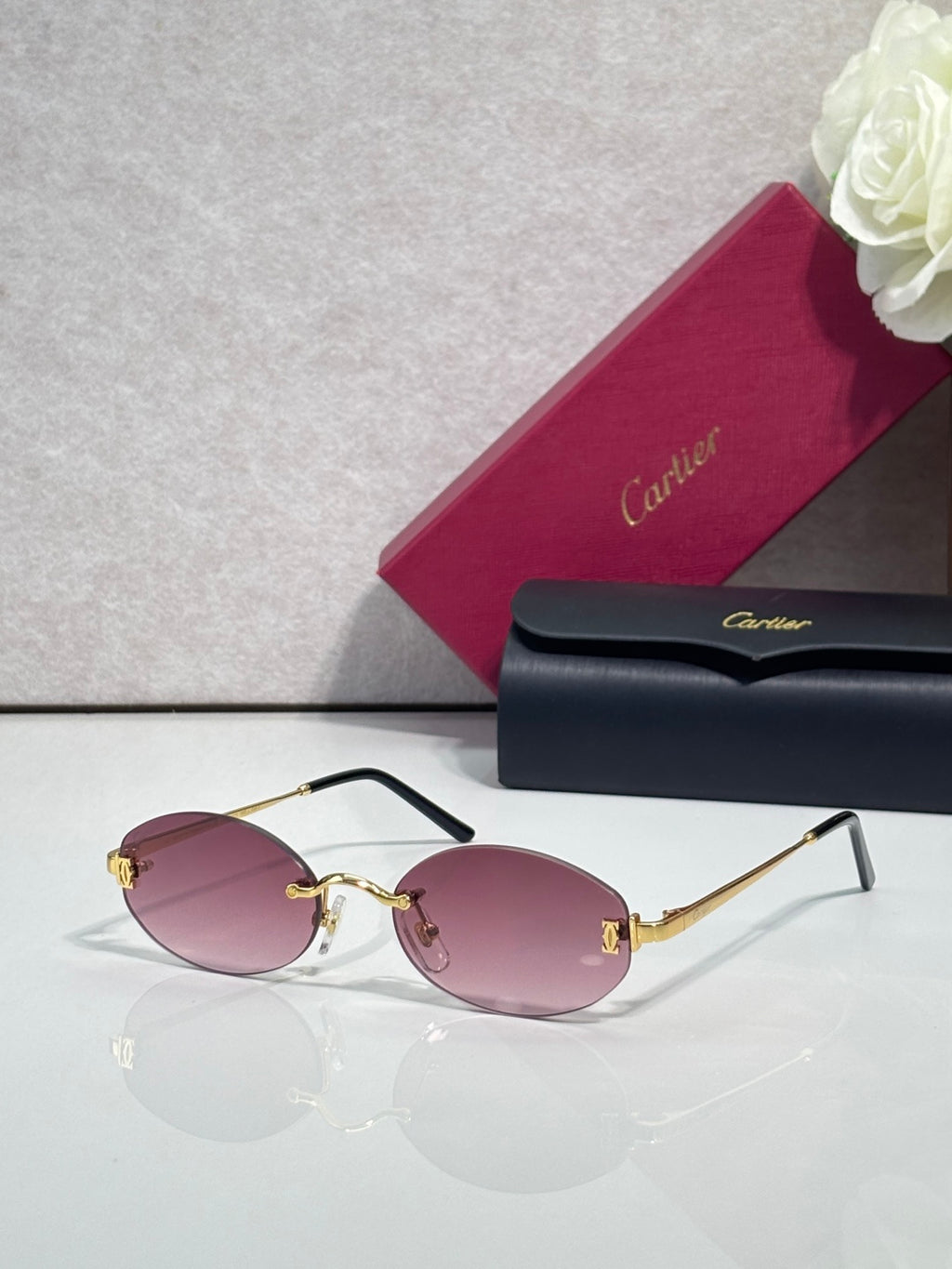 Round sunglasses with gold frame, dark temples, and pink tinted lenses