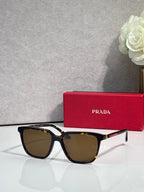 Prada sunglasses with dark tortoise-style frames, red side accents, and brown lenses.