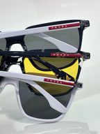 Prada sunglasses close-up with white frames, red temple details, and dark lenses.