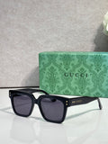 Gucci square sunglasses with dark lenses and black frame, gold stud accents on temples