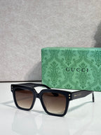 Gucci square sunglasses with dark lenses and black frame, gold detail studs on temple arms