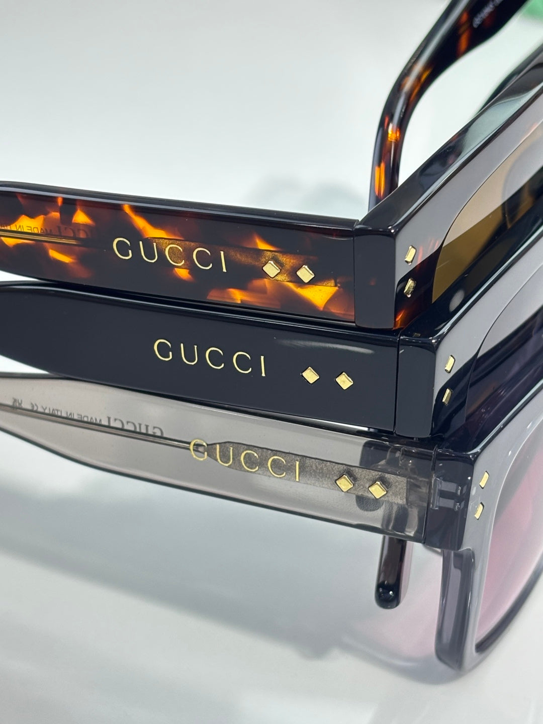 Gucci sunglasses close-up showing temple arms and gold stud details on black frame