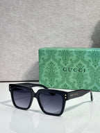 Gucci square sunglasses with dark lenses and black frame, front view with gold logo on temple