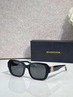 Black square sunglasses with gray-tinted lenses and gold logo temple detail