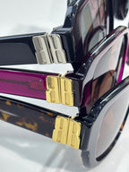 Sunglasses temple hardware with gold logo blocks on purple and dark frames