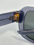 Sunglasses hinge with gold logo plate on dark blue frame temple