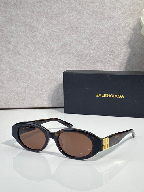 Balenciaga sunglasses with brown-tinted lenses, dark frames, and gold logo detail