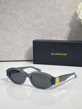Balenciaga sunglasses with dark lenses, black frames, and gold logo detail