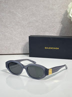 Balenciaga sunglasses with dark lenses, black frames, and gold logo detail