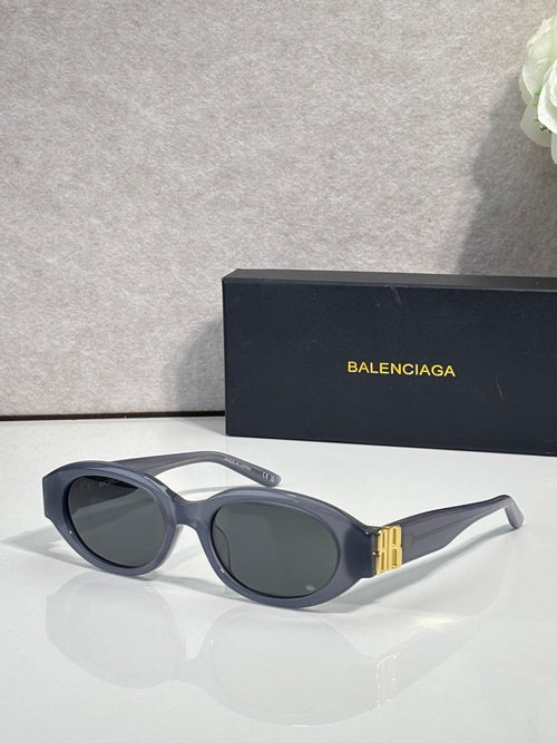 Balenciaga sunglasses with dark lenses, black frames, and gold logo detail